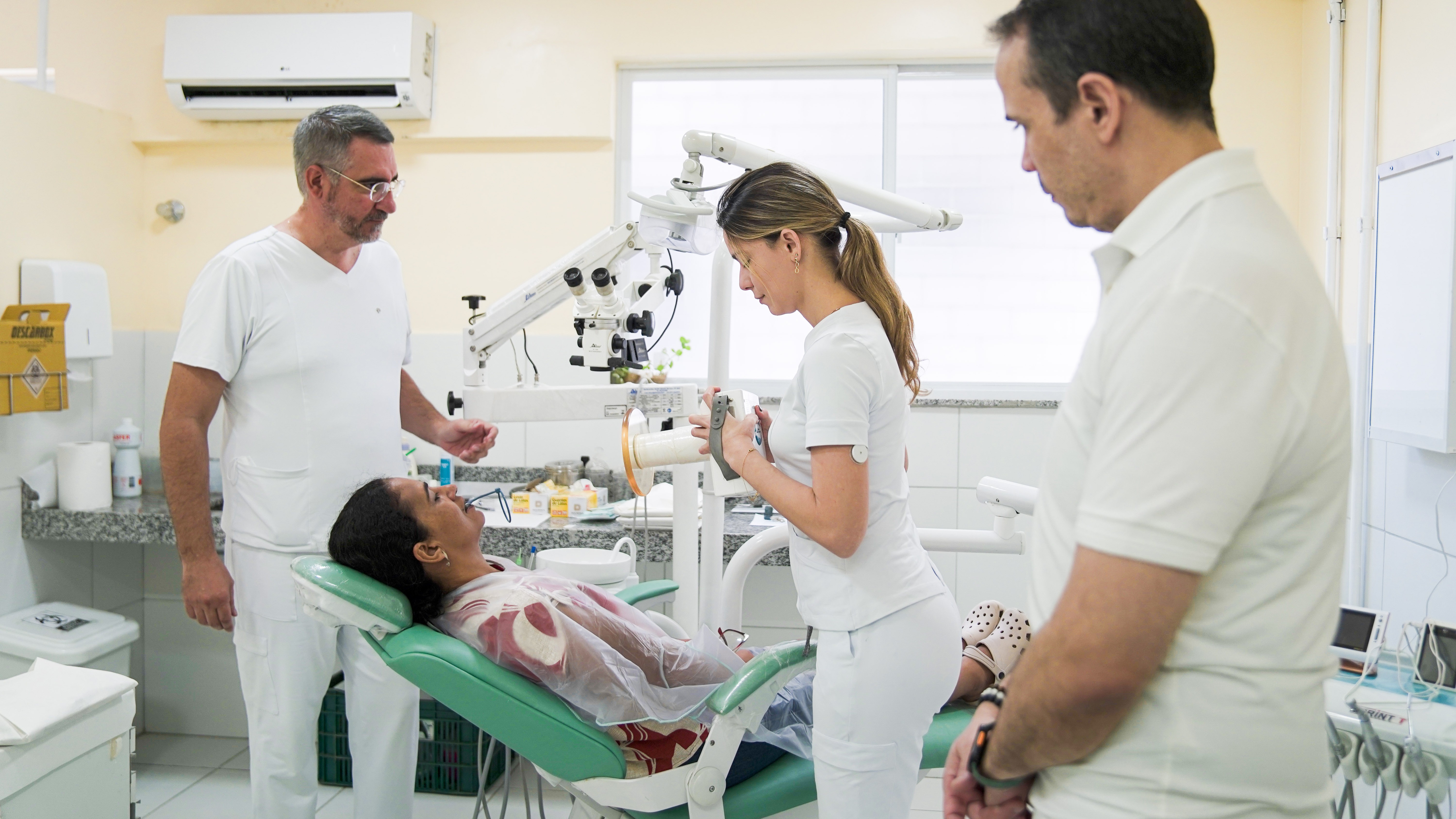 A foto mostra uma paciente sendo atendida em um consultório odontológico